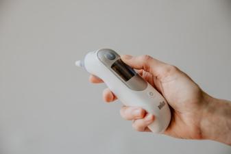 A hand holding a medical thermometer