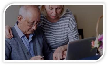 An elderly couple look at a laptop